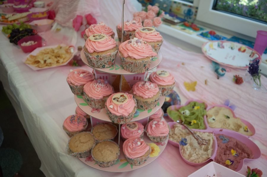 Tiered display of pink frosted cupcakes and party treats